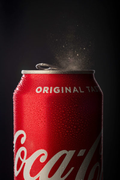 coke can close up with fizz escaping from the popped top