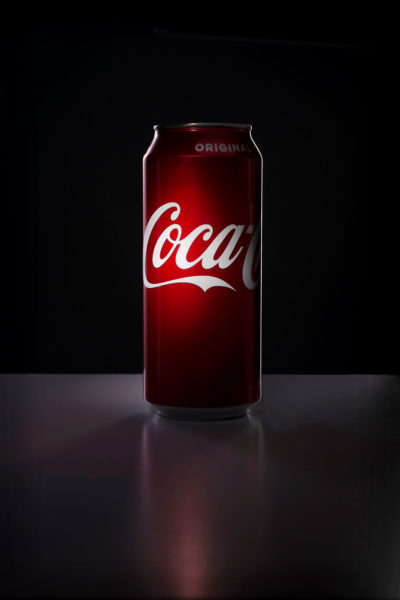dark mysterious photograph of a coke can spotlight on coke logo